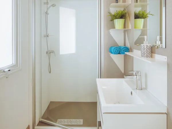 Bagno Roan Premium Lounge con cabina doccia e lavabo con mobile.