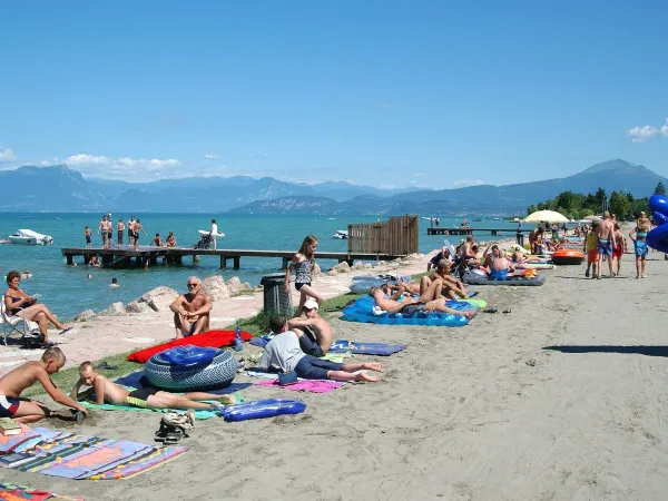 Spiaggia animata sul lago di Garda al Roan camping Del Garda.