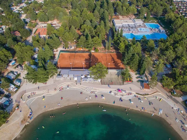 Vista aerea della spiaggia di ghiaia e del bar sulla spiaggia del campeggio Roan di Valkanela.