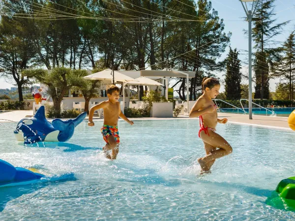 Bambini che corrono nella piscina poco profonda del campeggio Roan di Valkanela.