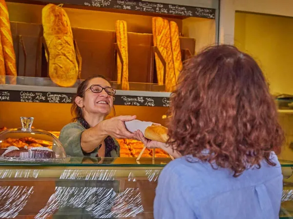 Una signora prende le baguette dalla panetteria del Roan camping Les Dunes.