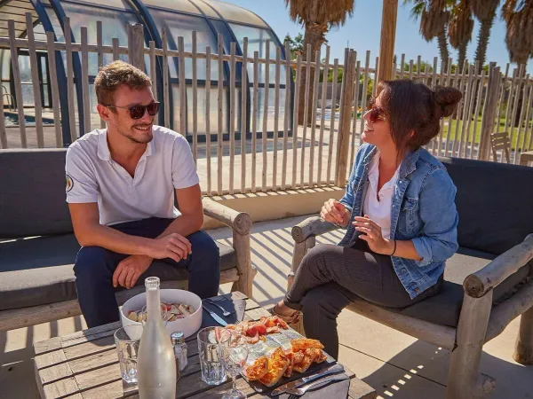 2 persone che bevono un drink sulla terrazza del Roan camping Les Dunes.