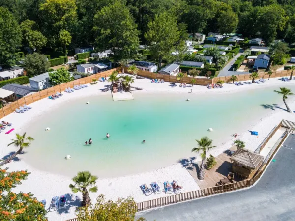 Panoramica della piscina lagunare con spiaggia sabbiosa del campeggio Roan La Clairière