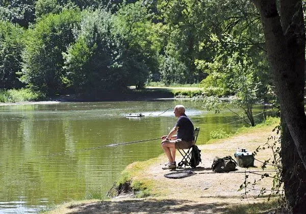 Uomo che pesca nel laghetto del campeggio Roan Domaine de la Brèche.