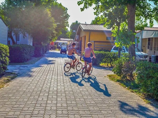 2 ragazzi attraversano in bicicletta il campeggio Roan Sole Family Camping Village.