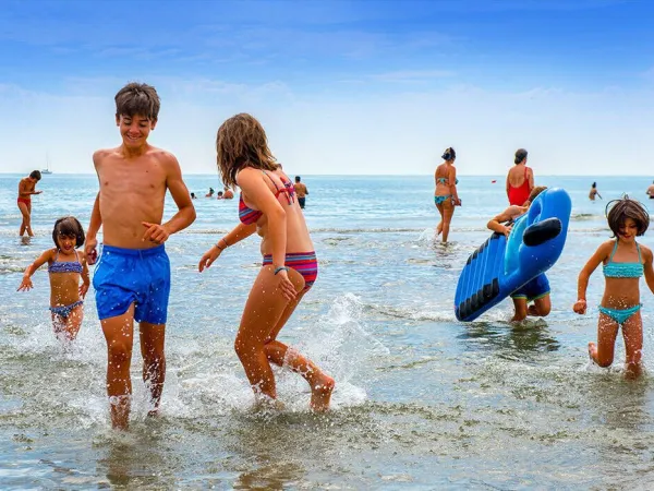 I bambini giocano nel mare del campeggio Roan Sole Family Camping Village.