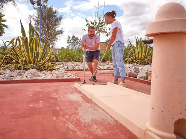 2 adulti giocano una partita di minigolf al campeggio Roan Les Dunes.