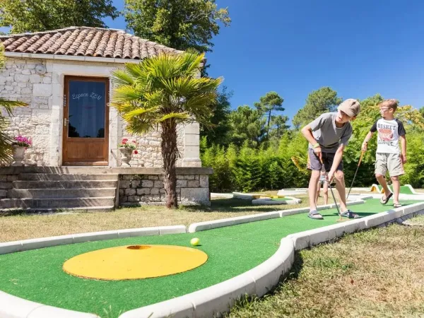 I bambini giocano a mini-golf al campeggio Roan La Clairière