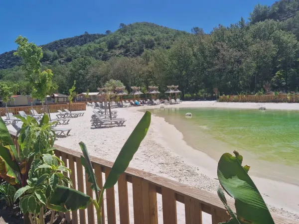 Piscina lagunare con spiaggia sabbiosa e lettini al campeggio Roan Verdon Parc.