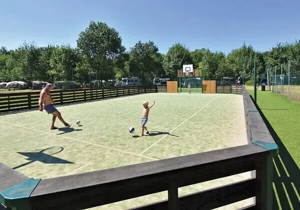 Padre e figlio giocano a calcio sul campo da calcio del campeggio Roan Domaine de La Brèche.