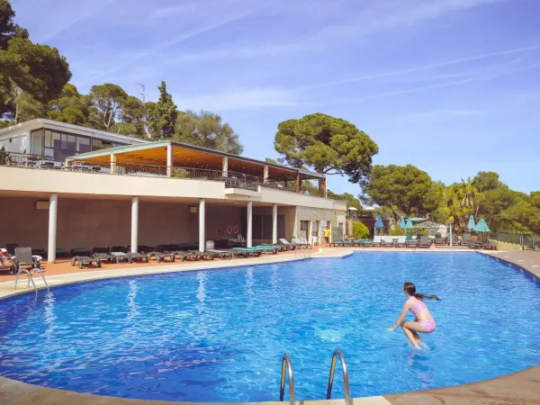 Ragazza fa un salto in piscina al campeggio Roan Internacional de Calonge.