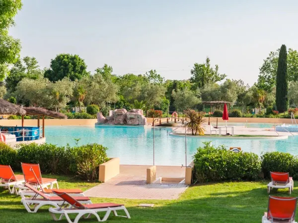 Prato erboso con piscina e bar a bordo piscina al Roan camping Le Capanne.
