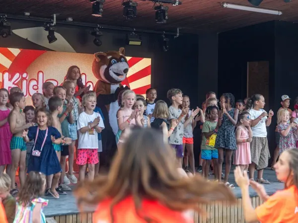 Bambini che cantano allegramente sul palco del campeggio Roan Château de Fonrives.
