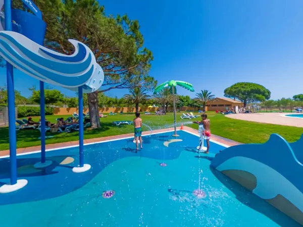 Spray park e area solarium con lettini all'ombra al Roan camping Platja Brava.