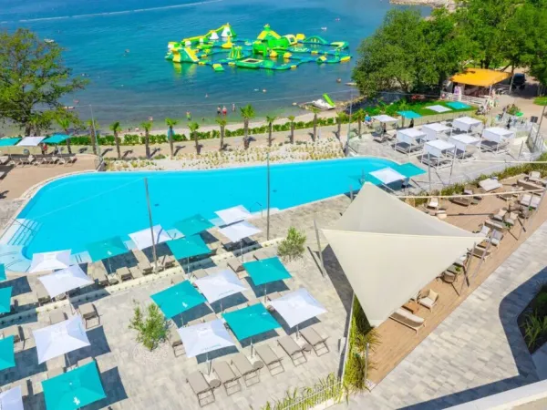 Panoramica della spiaggia di ghiaia e della piscina del campeggio Roan di Bijela Uvala.