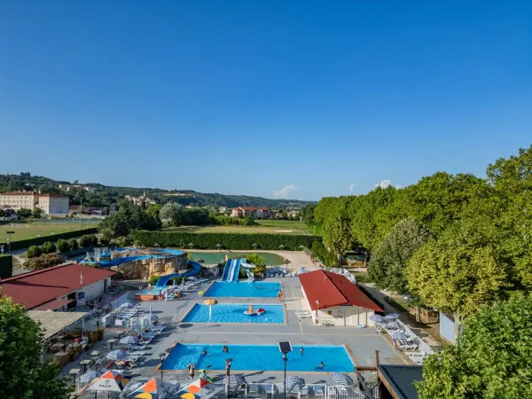 La piscina con scivoli e la terrazza adiacente del Roan camping Château de Galaure.