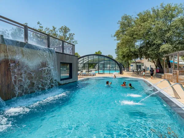 Piscina con cascata e irrigatori al campeggio Roan Domaine de Massereau.