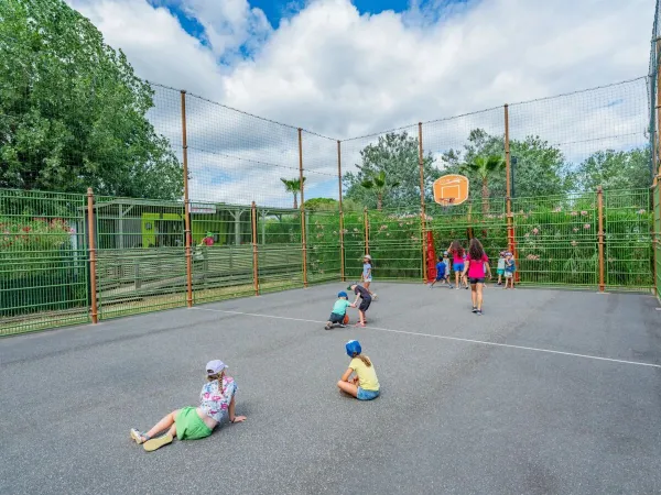 I bambini giocano nel campo sportivo polivalente del campeggio Roan Les Méditerranées Beach Garden.