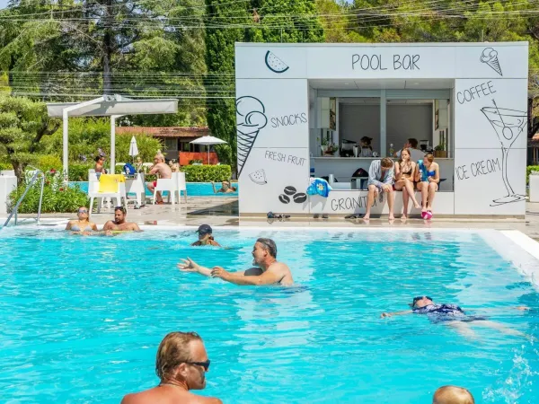 Persone che nuotano e si rilassano al bar della piscina del campeggio Roan di Valkanela.