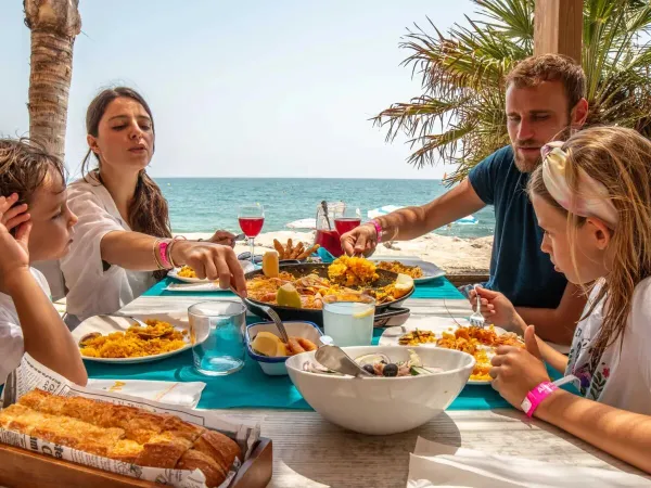 Una famiglia siede a mangiare sulla spiaggia del campeggio Roan Alannia Els Prats.