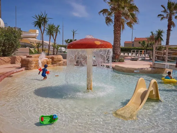 Piscina per bambini con scivolo e irrigatore a fungo al campeggio Roan Le Petit Mousse.