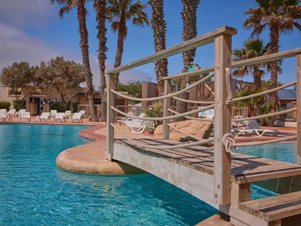 Ponte e lettini a bordo piscina al campeggio Roan Le Petit Mousse.