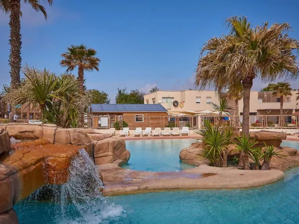 Bellissima piantumazione a bordo piscina con cascata al campeggio Roan Le Petit Mousse.