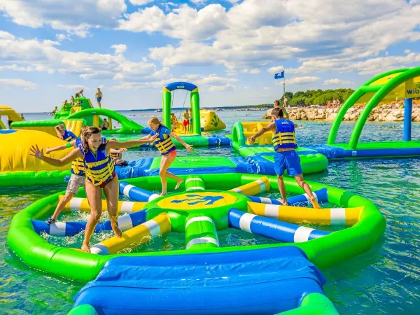 I bambini giocano sui cuscini d'aria nel lago del campeggio Roan Le Lac des Vieilles Forges.