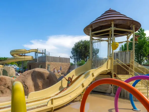 Una bambina scivola sullo scivolo per bambini del campeggio Roan Arinella Bianca.