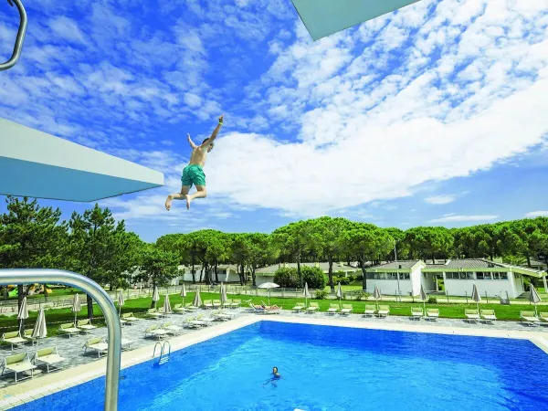 Bambino salta dal trampolino più alto del campeggio Roan Marina Julia Camping Village.
