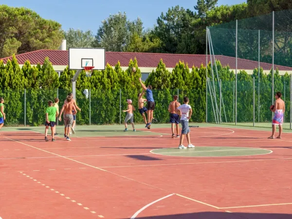 I bambini giocano a basket nel campo polisportivo del campeggio Roan Marina Julia Camping Village.