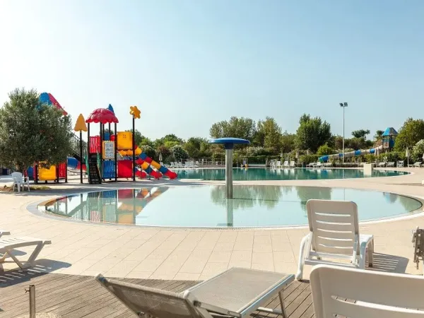 Piscina con lettini e parco giochi al campeggio Vigna sul Mar.
