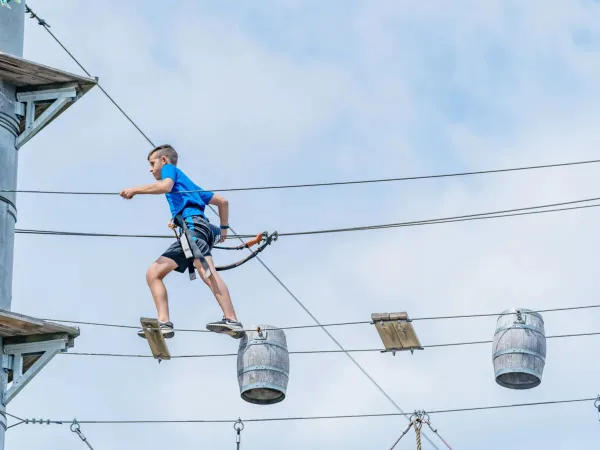 Un bambino si arrampica sul percorso di arrampicata del campeggio Roan Le Lac des Vieilles Forges.