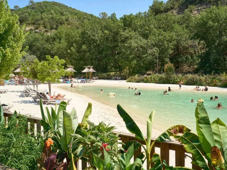 Piscina lagunare con spiaggia sabbiosa e lettini al campeggio Roan Verdon Parc.
