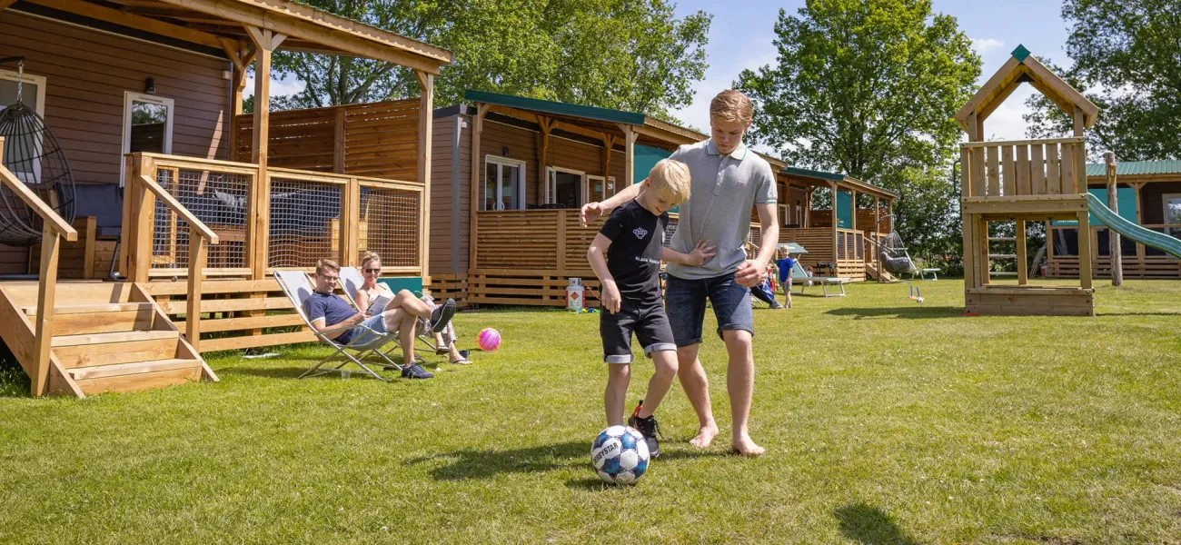 Bambini che giocano a calcio davanti a una casa mobile in un campeggio di Roan.